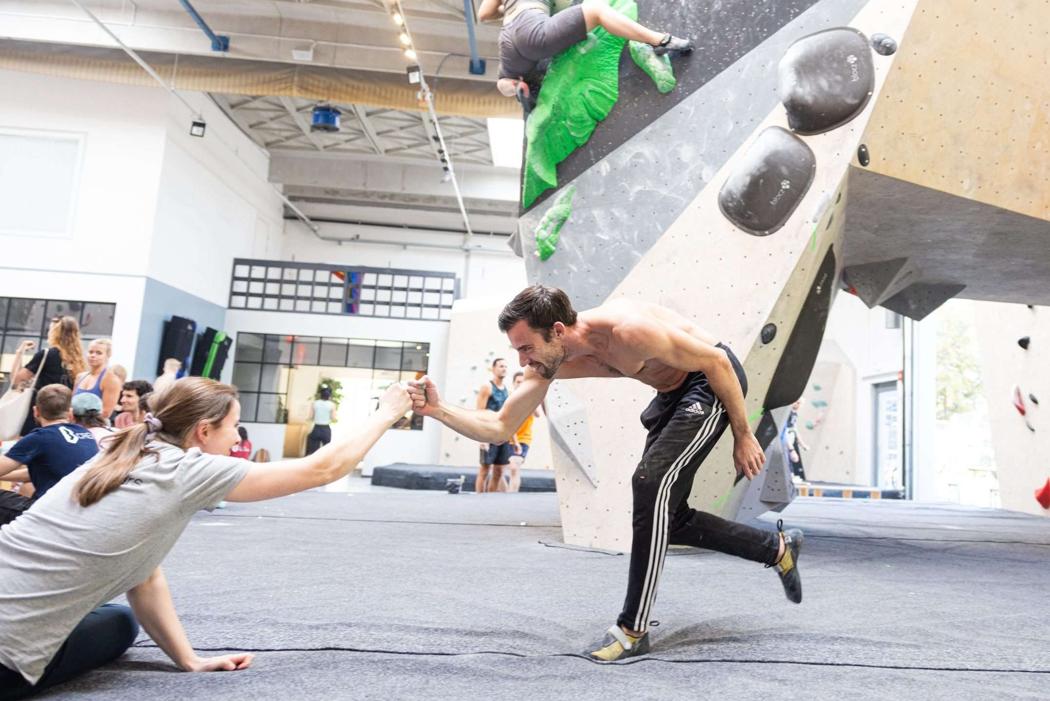 two people fist bumping in a climbing gym